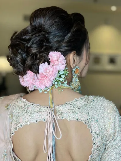 For this bride, I created a textured updo and decorated it with soft pink carnations and baby's breath, a delicate and feminine combination.