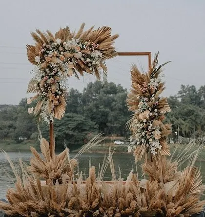 A modern, geometric arch decorated with pampas grass and white florals, creating a chic photo point for the anniversary celebration.