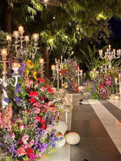 A pathway lined with an explosion of colorful flowers and candelabras, creating a grand entrance.