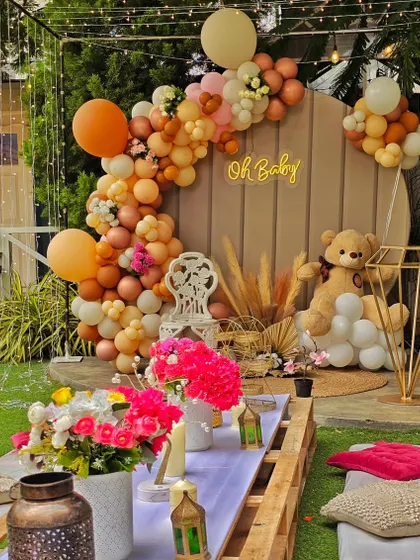 An outdoor "Oh Baby" celebration combining a picnic setup with a teddy bear theme. The wooden backdrop and earthy-toned balloon garland create a warm and inviting space for guests.