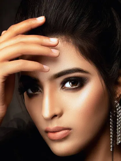 A classic beauty close-up with clean, elegant makeup. The hand gesture draws attention to the face, and the lighting creates a soft glow on the skin, resulting in a timeless and sophisticated portrait.