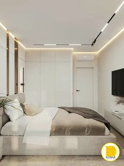 A bedroom with white, handleless wardrobes and bronze-colored mirror accents on the headboard wall.