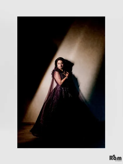 A stunning, low-light portrait of the bride in her dark gown. The single light source creates a dramatic, spotlight effect that is both artistic and beautiful.