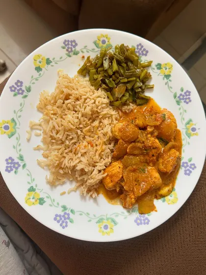 This meal includes brown rice with chicken curry and a side of sautéed green beans.