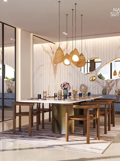 Dine in contemporary luxury. This space features a stunning marble-clad wall, a table with a sculptural brass base, and unique, organically shaped mirrors that reflect the warm glow of the pendant lights.
