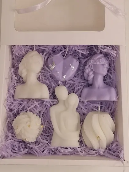 A lavender-themed bridesmaid gift box, filled with an assortment of sculptural candles like a couple candle, a heart candle, and goddess figures.