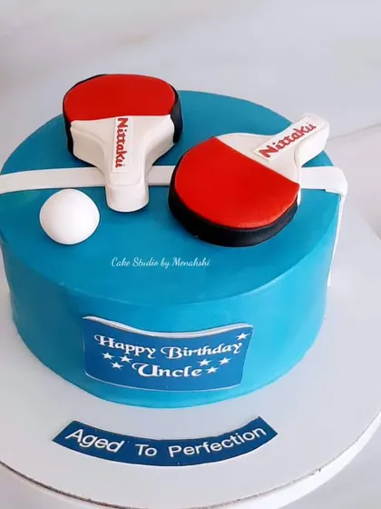 A cake for a table tennis lover, "aged to perfection." This design features two paddles and a ball on a bright blue cake.