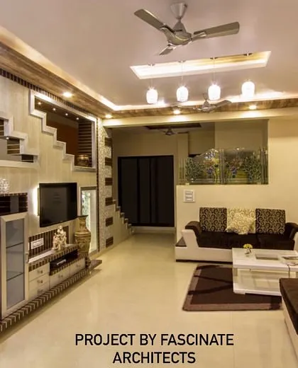 This large living room in Kharghar features an elaborate TV unit integrated with a staircase design. The use of mosaic tiles and multiple ceiling levels adds texture and dimension to the space.