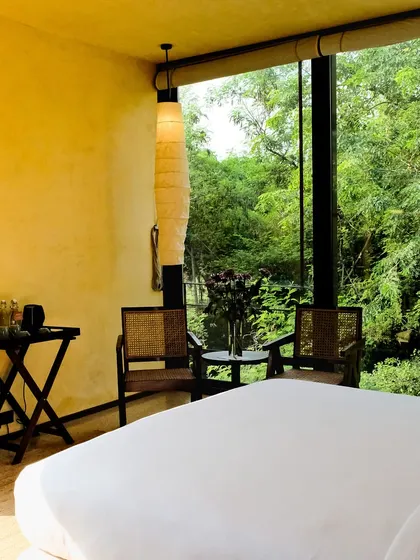 The full view of a suite, showing the spacious layout, minimalist furniture, and the all-encompassing view of the Asola Biosphere.