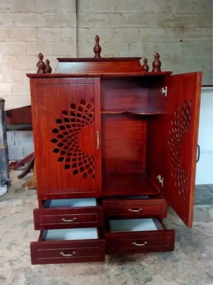 The interior of the compact pooja mandir, showing the open shelves for idols, integrated lighting, and pull-out drawers that provide ample and organized storage.