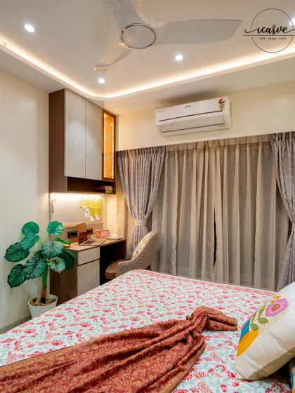 A bedroom designed with a compact study table and overhead storage, perfect for a student or professional.