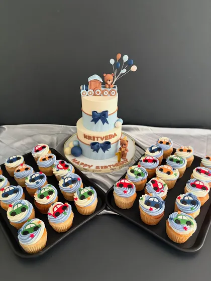 A sweet beginning for Kritveda's first birthday. This two-tiered teddy bear and train cake is paired with a set of matching car-themed cupcakes for all the guests.