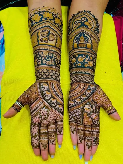 This design features a beautiful mix of peacocks, elephants, and kalash motifs. The use of color in the henna adds a unique and modern touch.