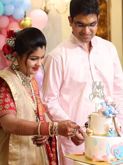 A beautiful moment as the parents-to-be cut their two-tiered baby shower cake during their Godh Bharai ceremony.