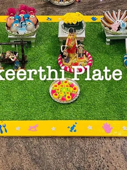 A closer look at a baby shower arrangement, featuring a miniature swing, cradle, and walker. These props add a playful and thematic touch to the seer varisai.