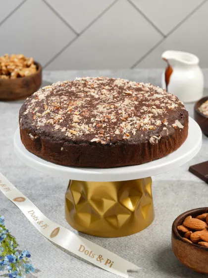 A full chocolate walnut cake presented on an elegant gold-accented stand. This type of hero shot is perfect for a bakery's homepage or promotional banner.