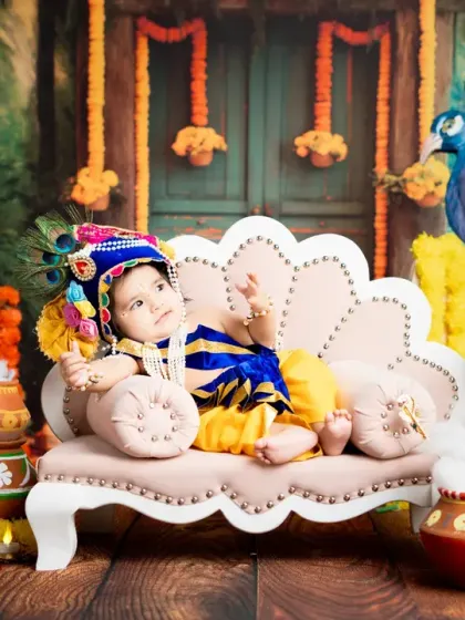 A relaxed and regal pose from a baby boy dressed as Krishna, lounging on his throne. The composition of this shot creates a beautiful and balanced portrait.