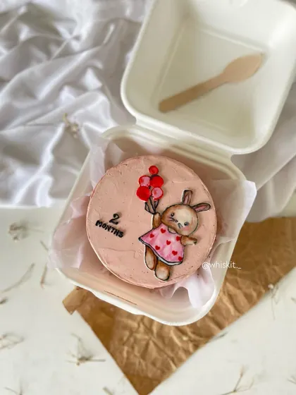 A bunny holding balloons on a pink bento cake for a 2-month celebration. The hand-drawn illustration adds a personal and artistic touch.