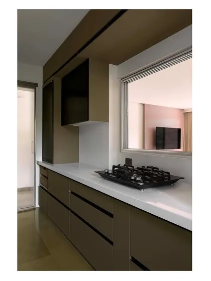 A sleek, modern kitchen design with handleless cabinets and a clean white countertop. A pass-through window connects the kitchen to the dining area, enhancing social interaction.