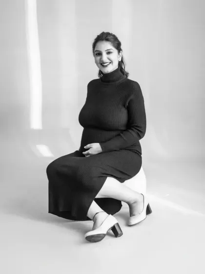 A joyful black and white portrait of the expecting mother. Her bright smile and confident pose radiate happiness. The simplicity of monochrome puts all the focus on her emotion.