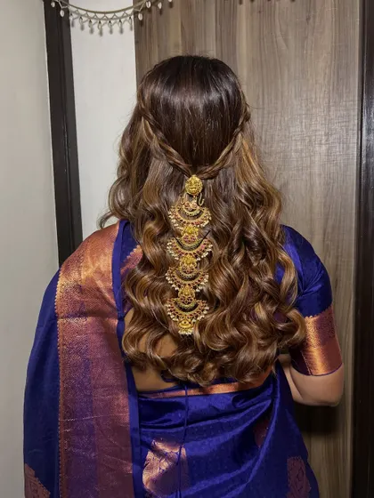 A back shot of the beautiful hairstyle I created for this bridesmaid. The half-up style with braids and curls is decorated with a traditional gold accessory.