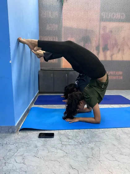 Welcome to our Malad West advance class. A student practices Pincha Mayurasana (Forearm Stand) variation against the wall to build strength and confidence.