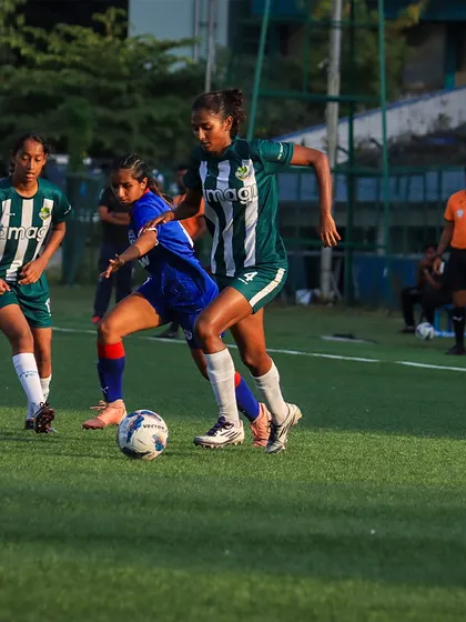A tense moment in the game as one of our players battles for possession against a determined opponent in blue.