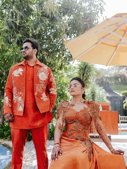 The power couple. A stylish shot of the bride and groom in their coordinated orange outfits for the Carnival party, looking effortlessly cool.