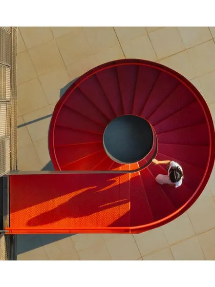 The 'Hoverspace' office extension features a scarlet spiral staircase as a key external feature. It provides a fire escape route while also acting as a sculptural counterpoint to the building's linear form, adding a bold splash of color.