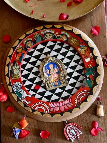 A hand-painted homage to the goddess Durga, housed within a restored vintage clock frame and a salvaged brass Prabhavali. This piece is inspired by the protective spirit of a dreamcatcher and the narrative style of Pattachitra art, adorned with found-object trims to complete its story.