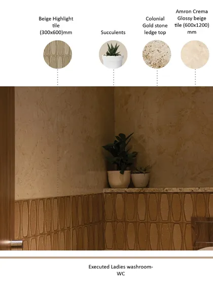 The executed ladies' WC combines different tile textures for a subtle, layered effect. A beige highlight tile creates a wainscoting effect, while succulents and warm, indirect lighting contribute to a tranquil and refreshing atmosphere.