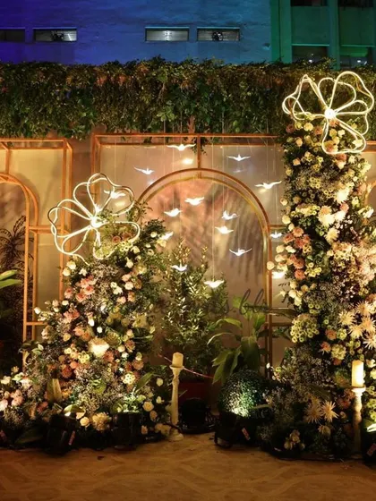 A nighttime view of the whimsical baby shower stage. The floral arrangements and neon lights create a magical glow, making the setting even more enchanting.