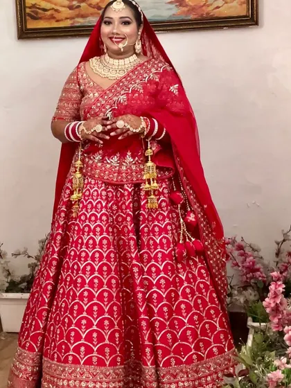 A full-length shot of a beautiful bride in a classic red lehenga, smiling brightly and showcasing her complete look without any filters.