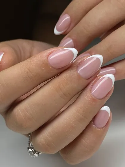 A classic French manicure on beautifully shaped oval nails. The crisp white tip and sheer pink base create a look of timeless elegance.