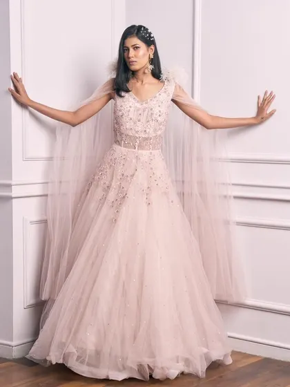 A full-length view of our fairytale pale pink gown with a feather-detailed cape.