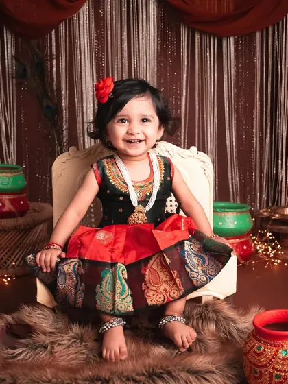 A beautiful, full smile from this little girl in her traditional dress. The warm lighting and festive background create a very inviting and happy portrait.