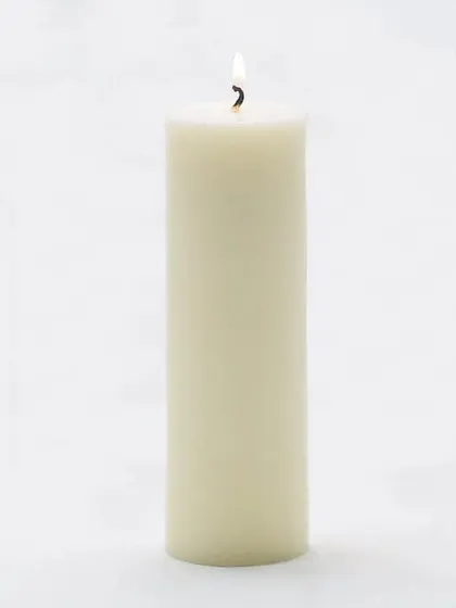 A single, tall white pillar candle lit to show its steady, clean-burning flame. I use high-quality paraffin wax to ensure a long-lasting and consistent burn for all my candles.