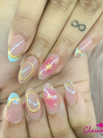 A celestial dream on your fingertips. This artistic set features a mix of pastel blue tips, gold outlines, and accent nails with a pink base and a golden starburst.