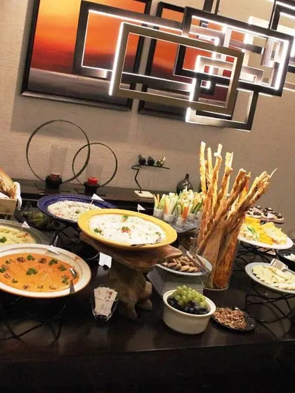 A wide shot of our buffet setup at an exclusive residence. The modern art and lighting in the background complement our contemporary food presentation, creating a cohesive and elegant atmosphere.