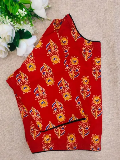 A red cotton boatneck blouse with a traditional paisley-like motif.