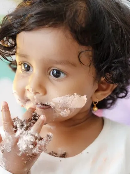 A close-up of the birthday girl enjoying her cake. The pastel rainbow theme is visible in the background, adding a touch of color.