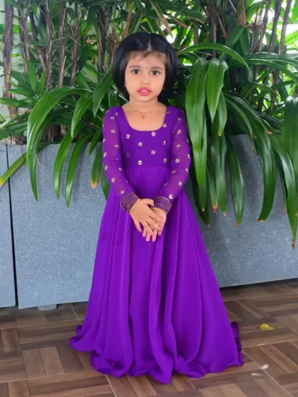 A full look at the custom purple gown. The square neckline and long, embellished sleeves add a sophisticated touch, making it a standout piece for any special celebration or photoshoot.