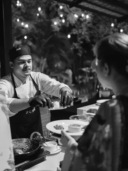 A guest interacts with one of our chefs at a live cooking station, receiving a freshly prepared dish.