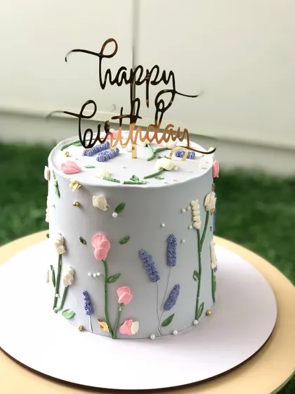 A dainty cake with a wildflower meadow design, hand-piped in delicate buttercream.
