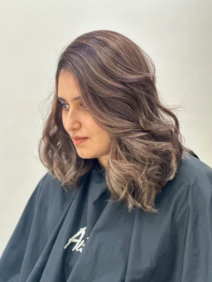 A beautiful transformation on medium-length hair. The soft brown highlights and wavy styling create a look that is both professional and stylish.
