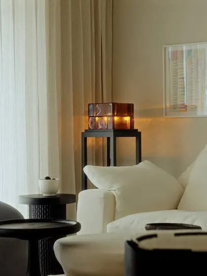 A quiet Sunday moment in Apartment O2. The warm glow of a glass table lamp creates a cozy and inviting atmosphere.