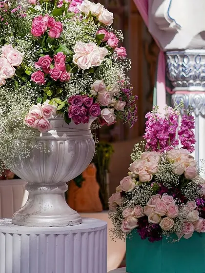 A large floral arrangement in a silver urn, featuring a mix of pink roses and baby's breath. The abundance of flowers is a key element of this romantic and whimsical theme.