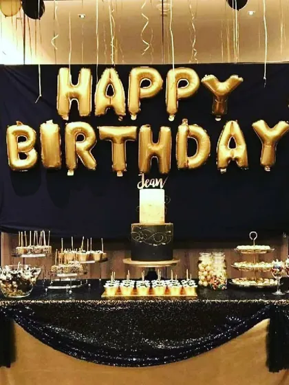 This birthday decoration in black and gold includes a backdrop and a decorated table, creating a perfect spot for the cake and desserts.
