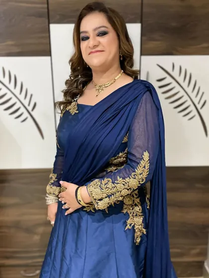 The complete look, showing how the intense smokey eye makeup is balanced by soft, flowing curls and an elegant navy blue gown with gold embroidery.