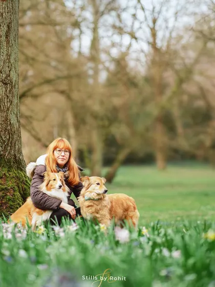 A lovely portrait of a woman with her two beautiful dogs, Bella and Monty, nestled among the daffodils. A perfect representation of a peaceful Sunday morning in the park.